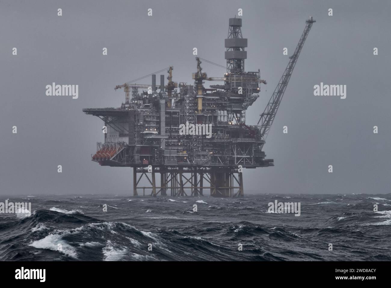 Plate-forme pétrolière et gazière offshore en mer, pendant la tempête, avec ciel gris et vagues au premier plan. Banque D'Images