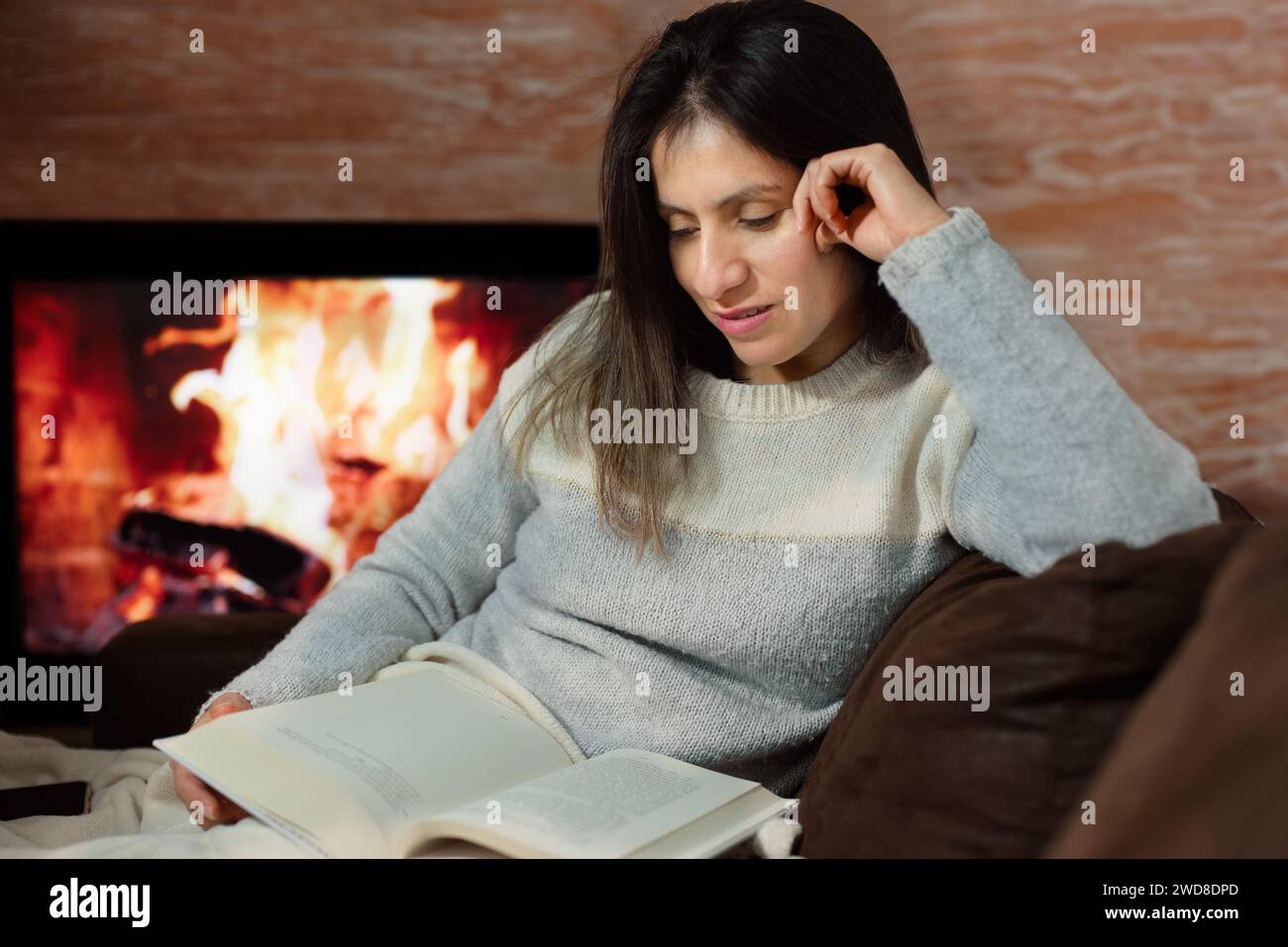 Femme aime lire un livre de son canapé à la maison. Banque D'Images