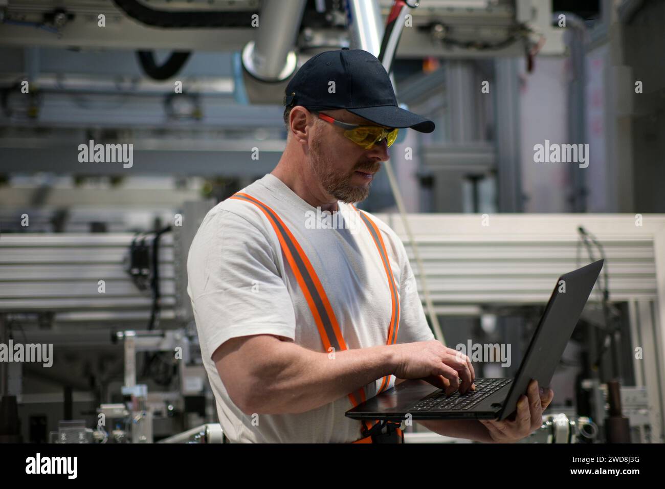 ingénieur en t-shirt blanc robot de programmation sur la chaîne de montage en utilisant l'arrière-plan flou d'ordinateur portable. Banque D'Images