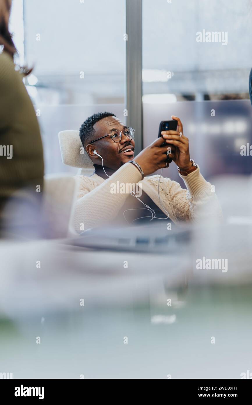 Employé de sexe masculin appréciant la pause au travail. Regarder des vidéos sur son téléphone. Banque D'Images