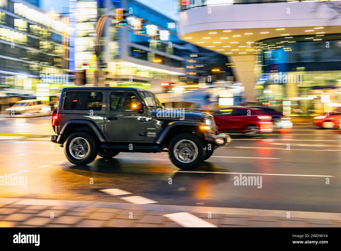 Innerstädtische Straße mit Fahrzeugen, moderne Architektur am Abend. Bewegungsunschärfe. Jeep Wrangler // 17.01.2024 : Stuttgart, Baden-Württemberg, Deutschland. *** Rue de la ville avec des véhicules, architecture moderne dans le soir mouvement flou Jeep Wrangler 17 01 2024 Stuttgart, Baden Württemberg, Allemagne Banque D'Images