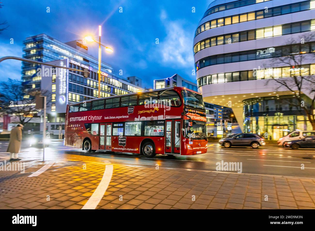 Tour de ville de Stuttgart. Stadtrundfahrt im roten Doppeldecker. Innerstädtische Straße mit Fahrzeugen, moderne Architektur am Abend. Bewegungsunschärfe. // 17.01.2024 : Stuttgart, Bade-Württemberg, Deutschland. *** Stuttgart citytour visite de la ville dans une rue rouge à deux étages avec des véhicules, architecture moderne dans la soirée Motion blur 17 01 2024 Stuttgart, Baden Württemberg, Allemagne Banque D'Images