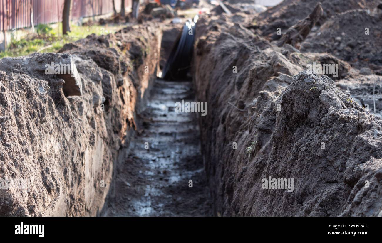 Terrassement. Une longue tranchée profonde creusée dans le sol pour la pose de câbles, de tuyaux. Banque D'Images