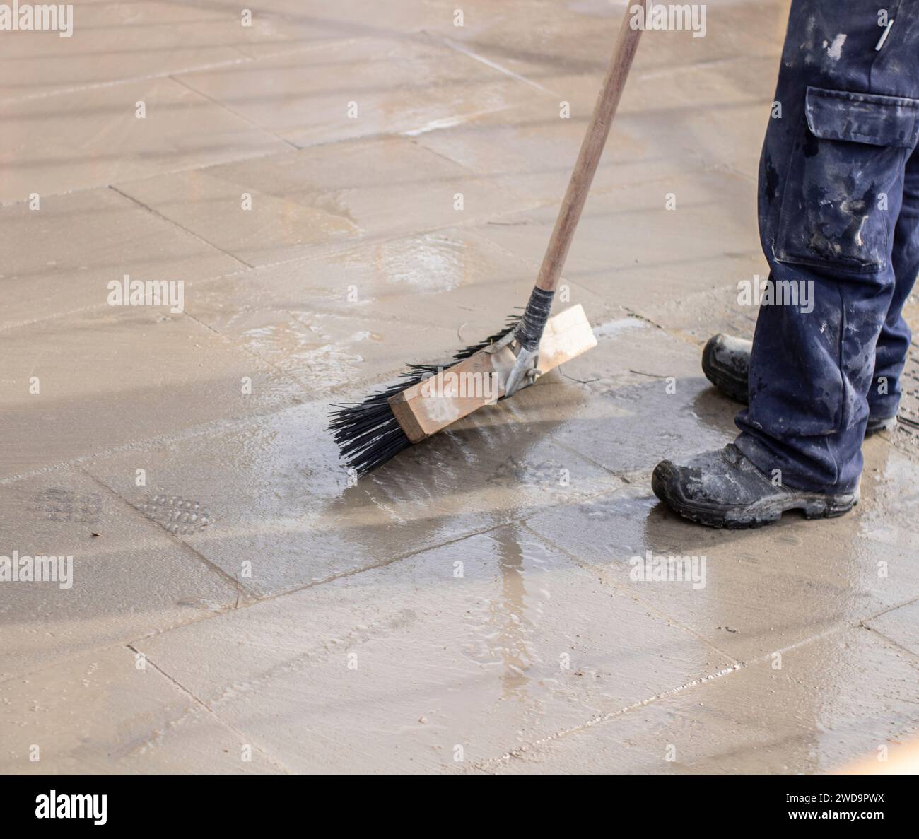 L'employé municipal balaye la route avec le balai et ramasse les ordures dans la pelle. le travailleur de l'assainissement balaye la rue Banque D'Images