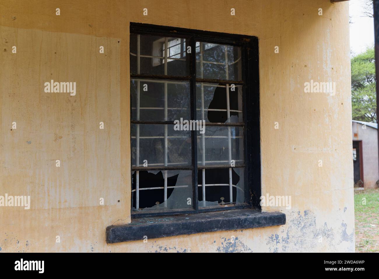 Fenêtre cassée avec barres anti-effraction sur un bâtiment ancien, architecture coloniale vintage dans un village du Botswana, éléments de design et textures Banque D'Images