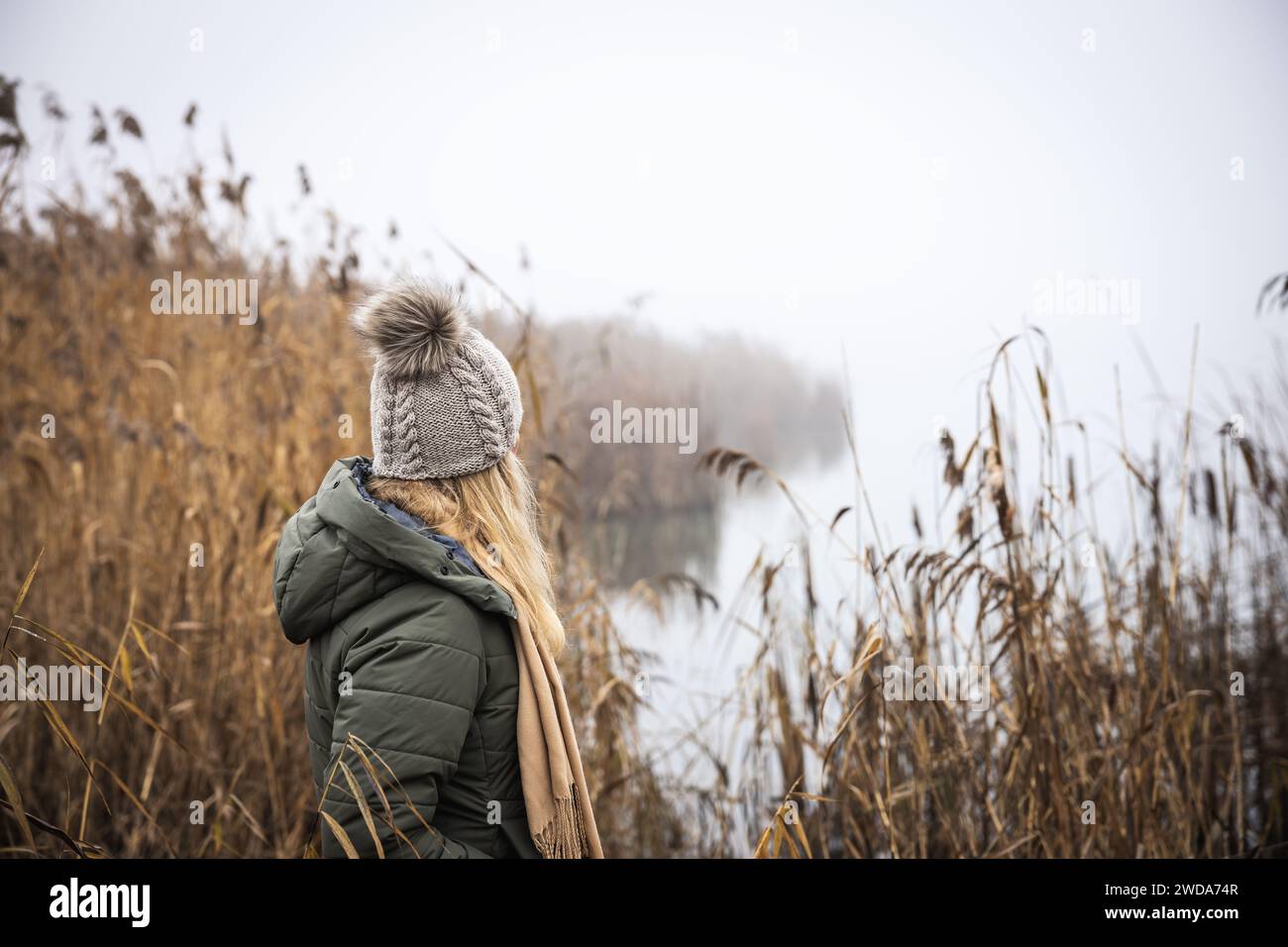 Femme triste solitaire debout près d'un lac brumeux. Dépression et état d'esprit anxieux Banque D'Images