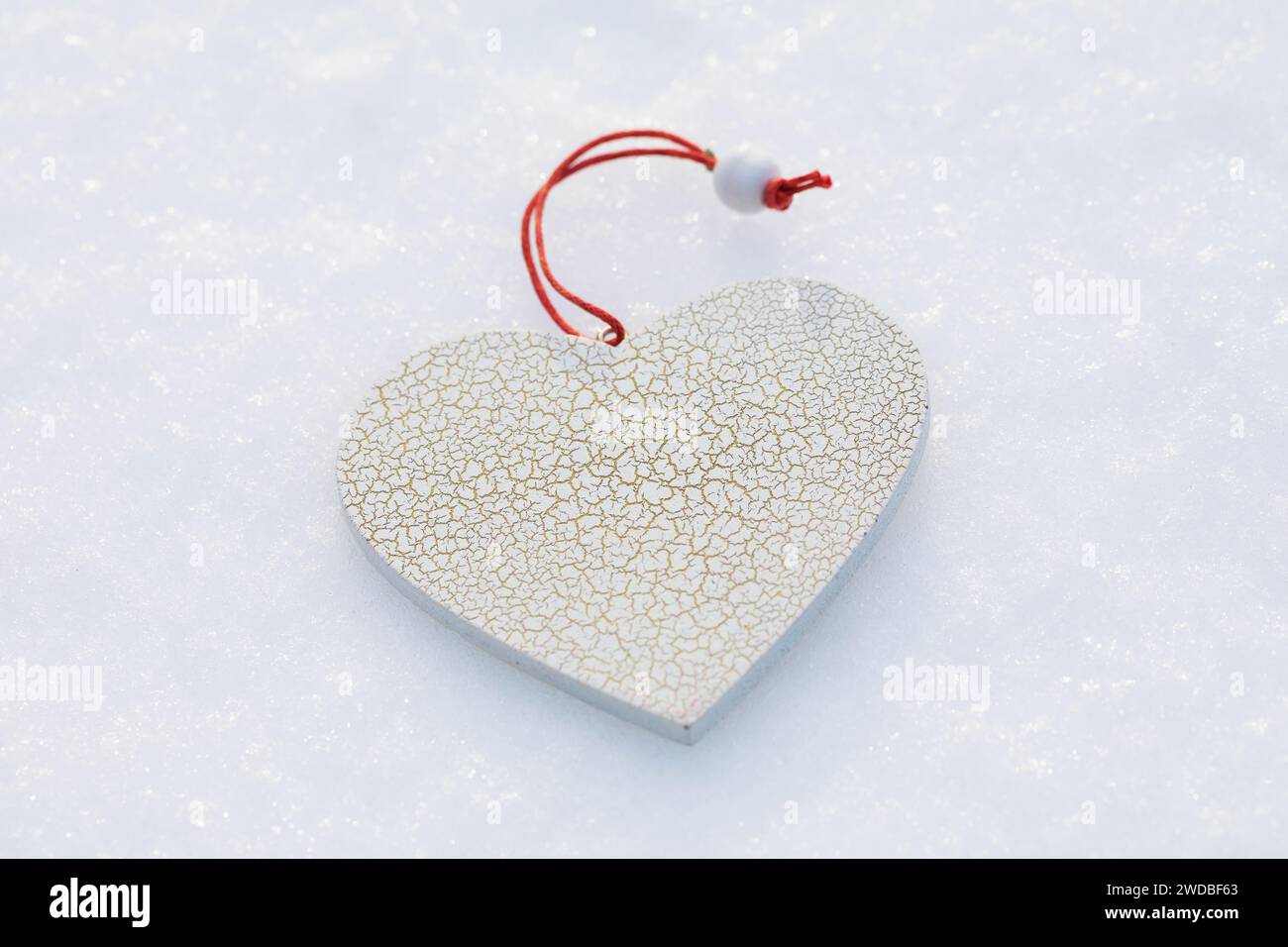 Jouet blanc en forme de coeur avec de petites fissures dans la neige, modèle pour le concepteur Banque D'Images