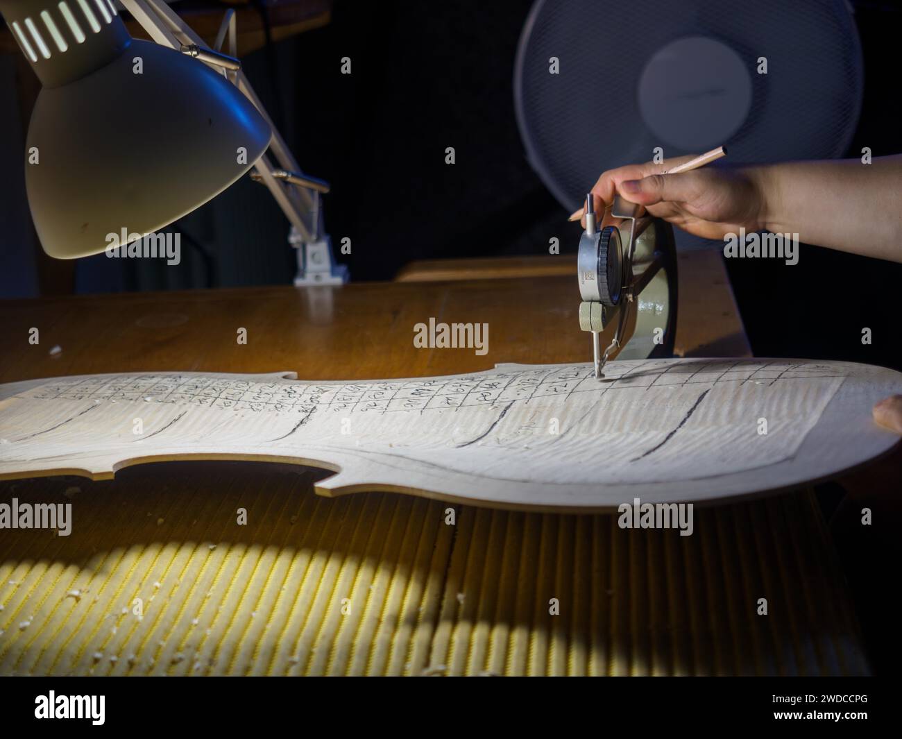 Gros plan de la main du maître luthier fabricant d'instruments à cordes procéder au travail de graduation en cours de violoncelle plaque arrière, en utilisant, jauge d'épaisseur Banque D'Images