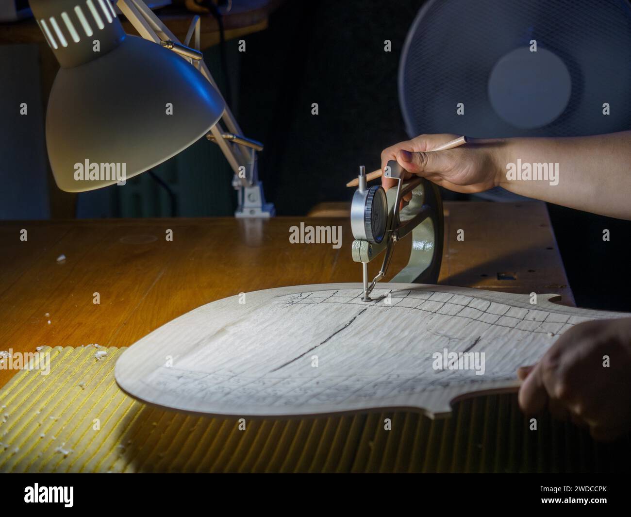 Gros plan de la main du maître luthier fabricant d'instruments à cordes procéder au travail de graduation en cours de violoncelle plaque arrière, en utilisant, jauge d'épaisseur Banque D'Images