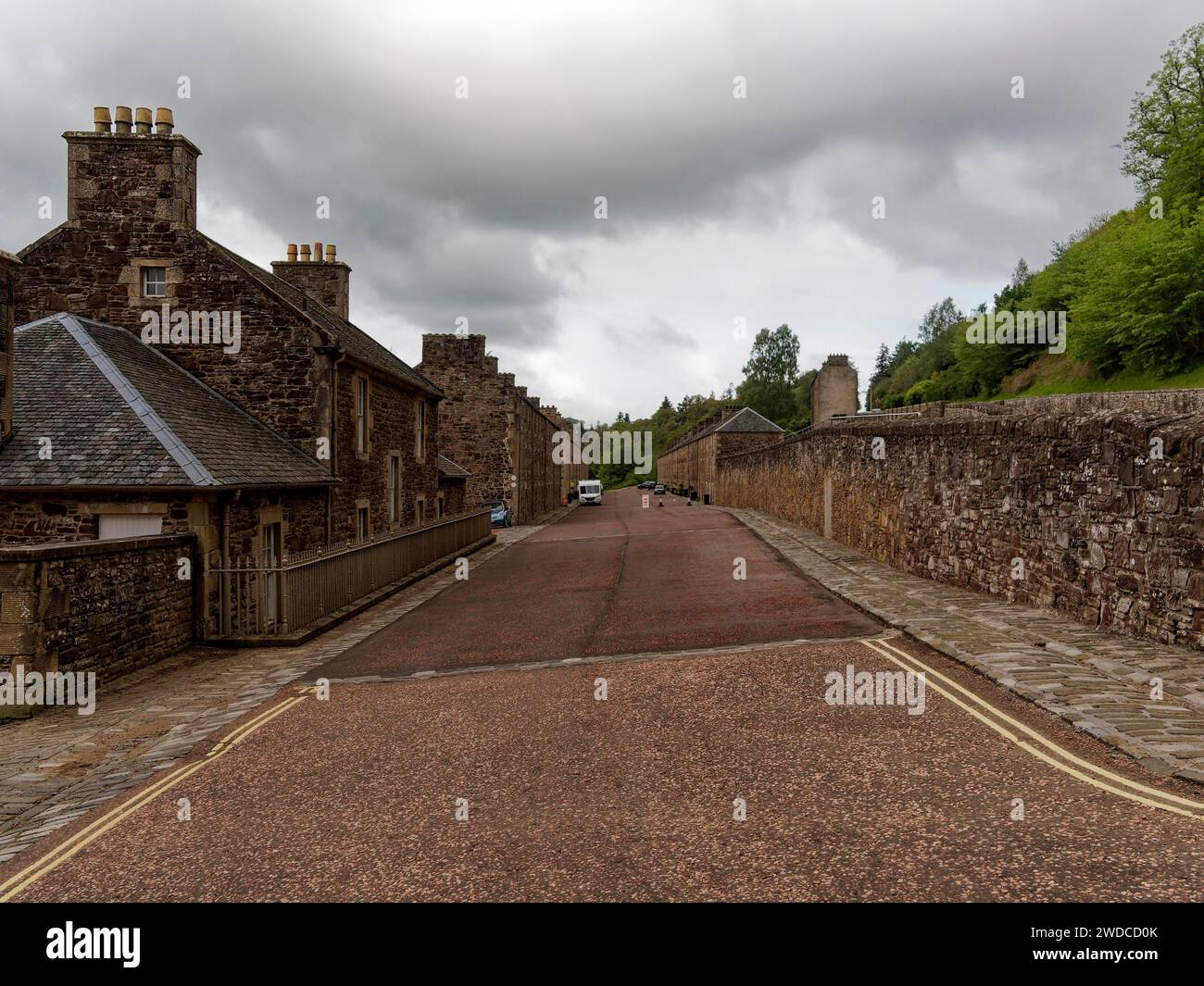 Une rue pavée mène devant des bâtiments historiques en pierre sous un ciel nuageux inquiétant, New Lanark. Site du patrimoine mondial de l'UNESCO, Écosse, Grande-Bretagne Banque D'Images