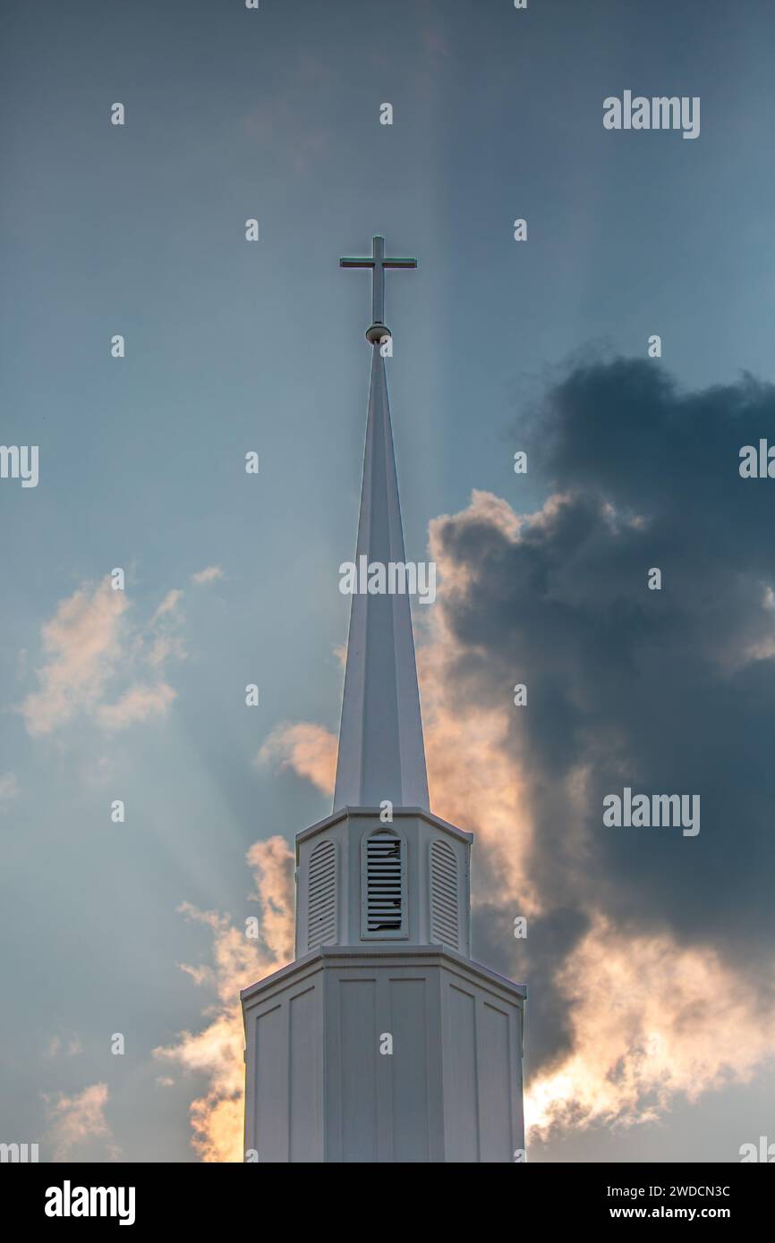 Clocher de croix et d'église avec soleil l'allumant et ciel bleu en arrière-plan, vertical Banque D'Images