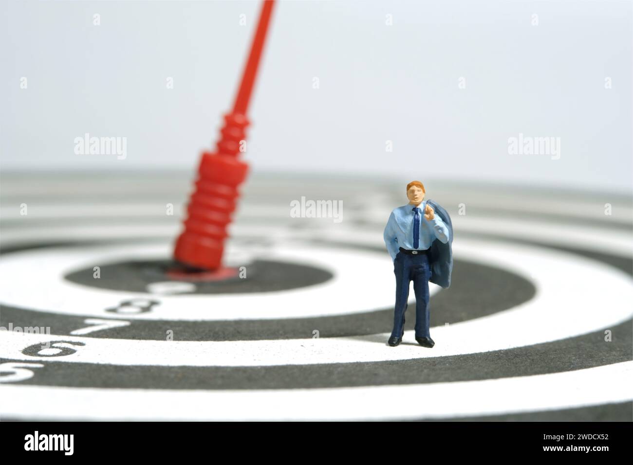 Photographie miniature de figurine de jouet de personnes minuscules. Illustration du concept d'entreprise. Un homme d'affaires debout au-dessus du jeu de fléchettes avec la flèche rouge, pensant la stratégie Banque D'Images