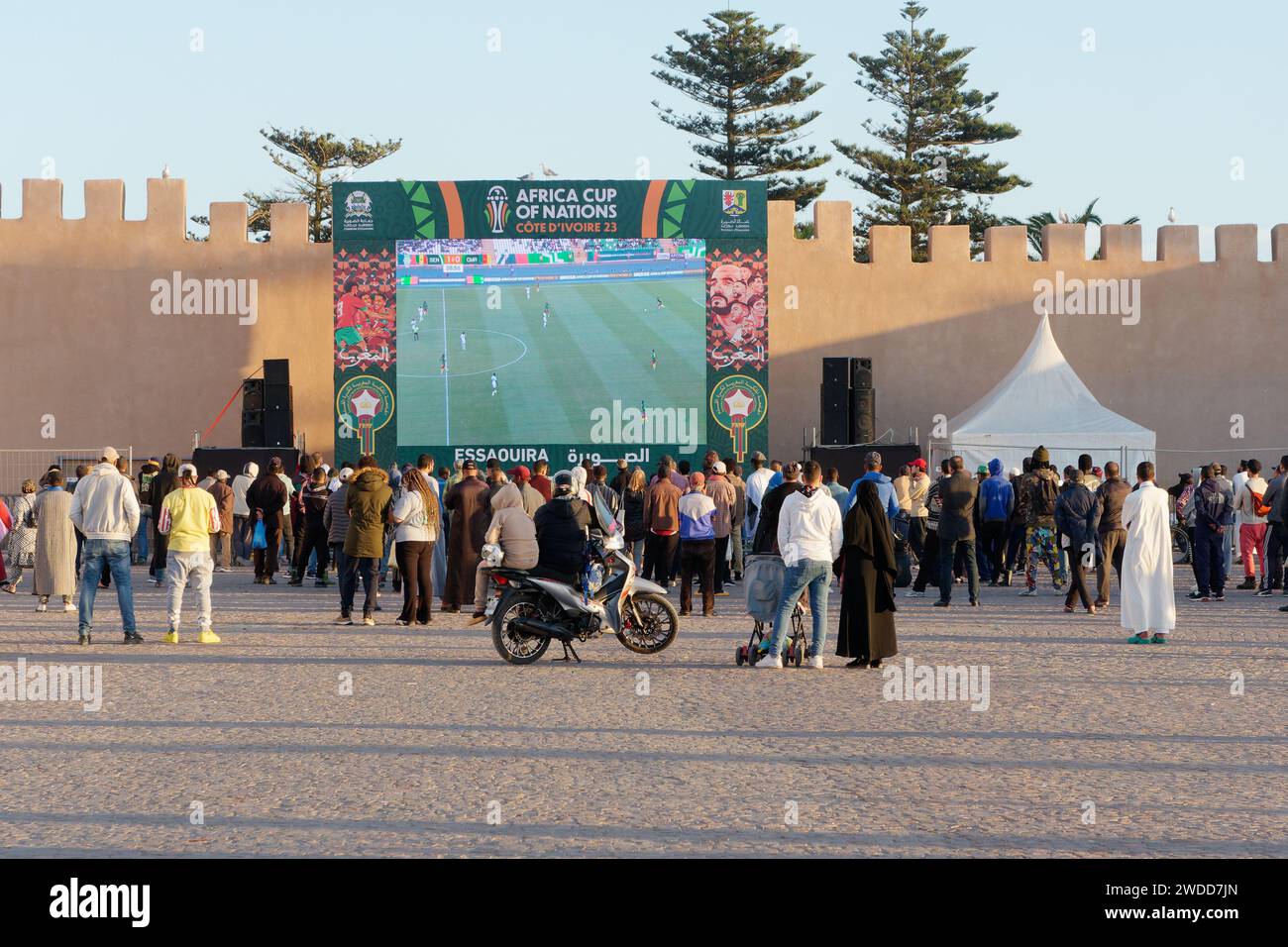 Les gens regardent un match de football de la Coupe d'Afrique des Nations dans une grande rue dans la soirée sur la place principale à Essaouira, Maroc, le 19 janvier 2024 Banque D'Images