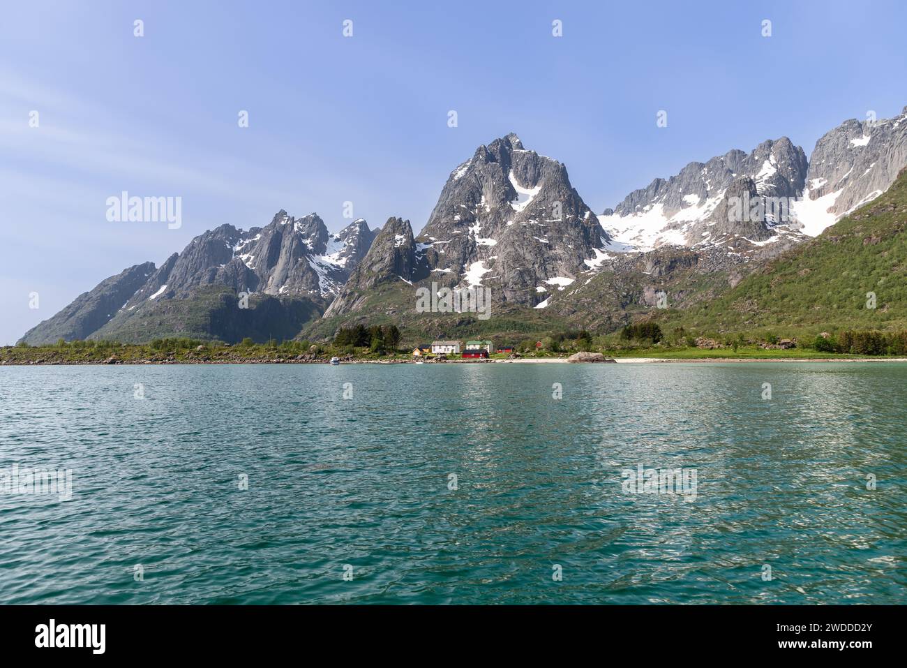 Nichée dans une rare étendue plate le long du fjord des Lofoten, une ferme solitaire revendique sa place sous les montagnes imposantes et accidentées Banque D'Images