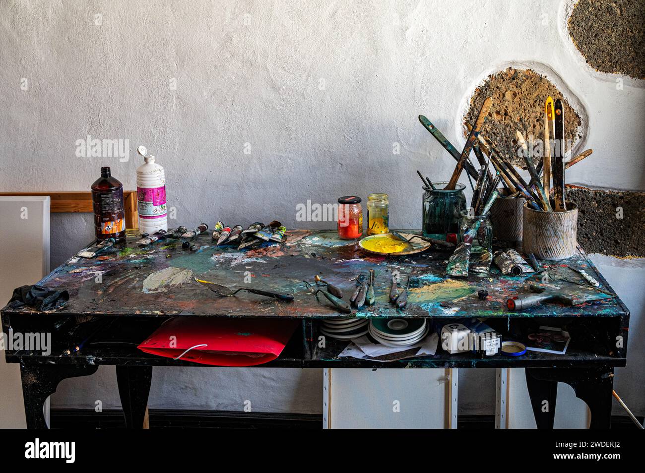 Table de Messy artiste avec pinceaux et autres fournitures d'art dans l'atelier d'art. Banque D'Images