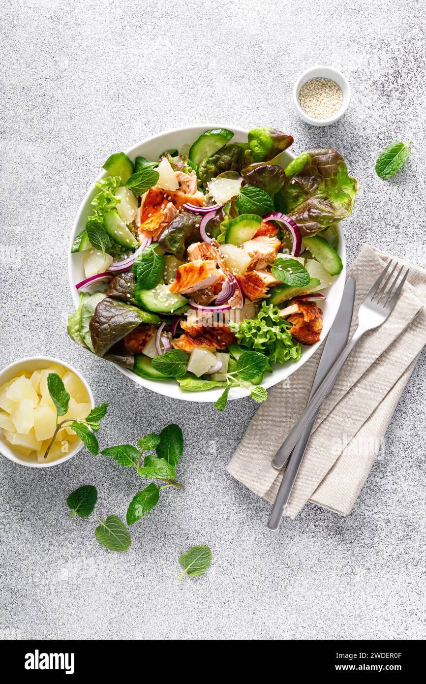 Salade avec saumon grillé, feuilles de salade verte fraîche, concombre, oignon rouge, menthe et ananas. Salade de déjeuner saine pour régime céto. Vue de dessus Banque D'Images