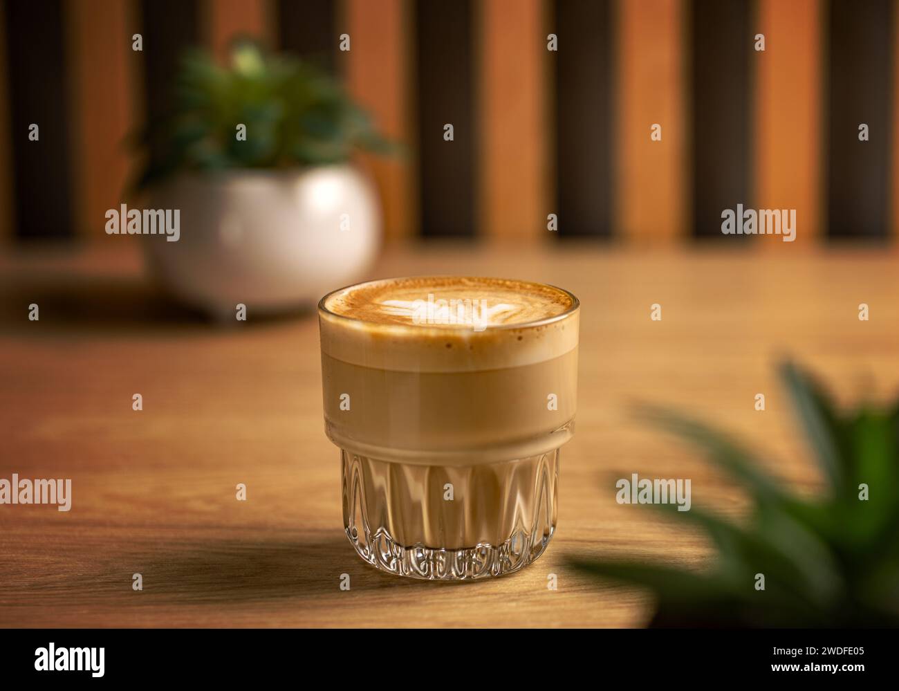 Lait crémeux chaud dans le café. Café blanc plat dans une tasse en verre transparent Banque D'Images