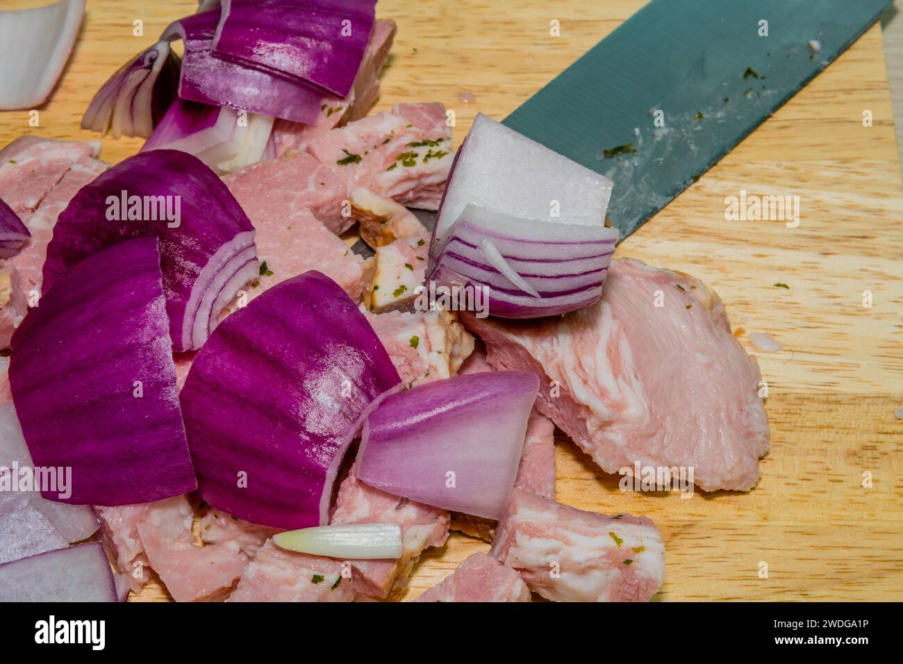 Gros plan des mandrins d'oignon et de jambon posés sur la planche à découper avec le couteau butch sous le jambon Banque D'Images