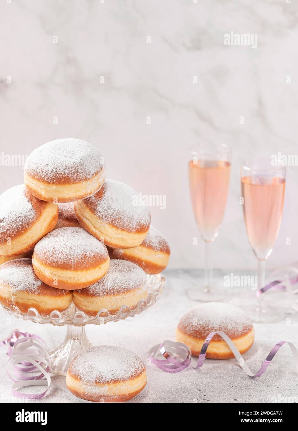 Beignets sur un support en verre avec vin mousseux rose en arrière-plan, salle de copie Banque D'Images