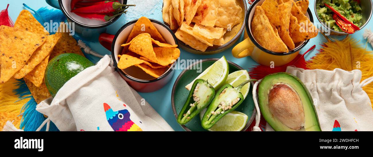 Concept Cinco-de-mayo. Nourriture traditionnelle nacho chips sauce salsa tequila Chili avec sel citron vert sombrero serape cactus et maracas sur fond bleu. Banque D'Images