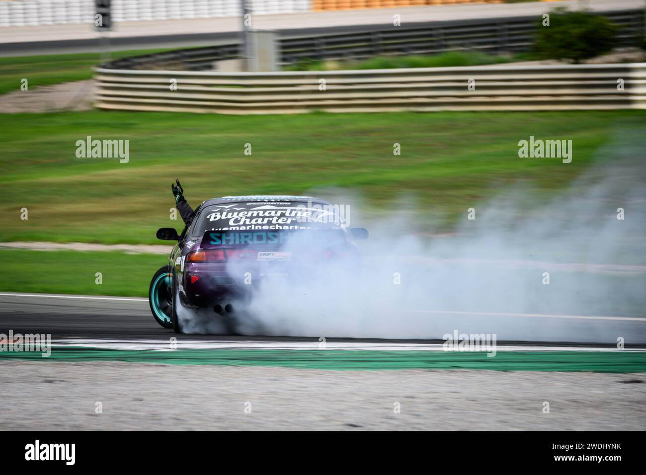 Voiture à grande vitesse dérivant de fumée et collant un bras par la fenêtre autour du circuit Ricardo Tormo à Cheste, Valence, Espagne Banque D'Images