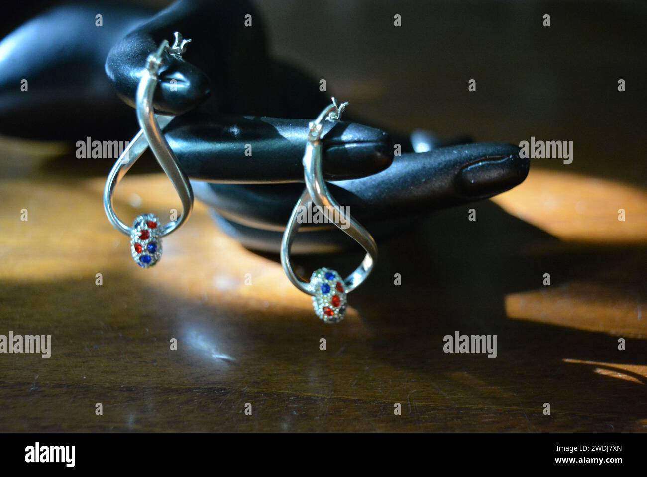 Statuette noire d'une main féminine mate avec boucles d'oreilles en argent avec de belles pierres et un pendentif. Banque D'Images