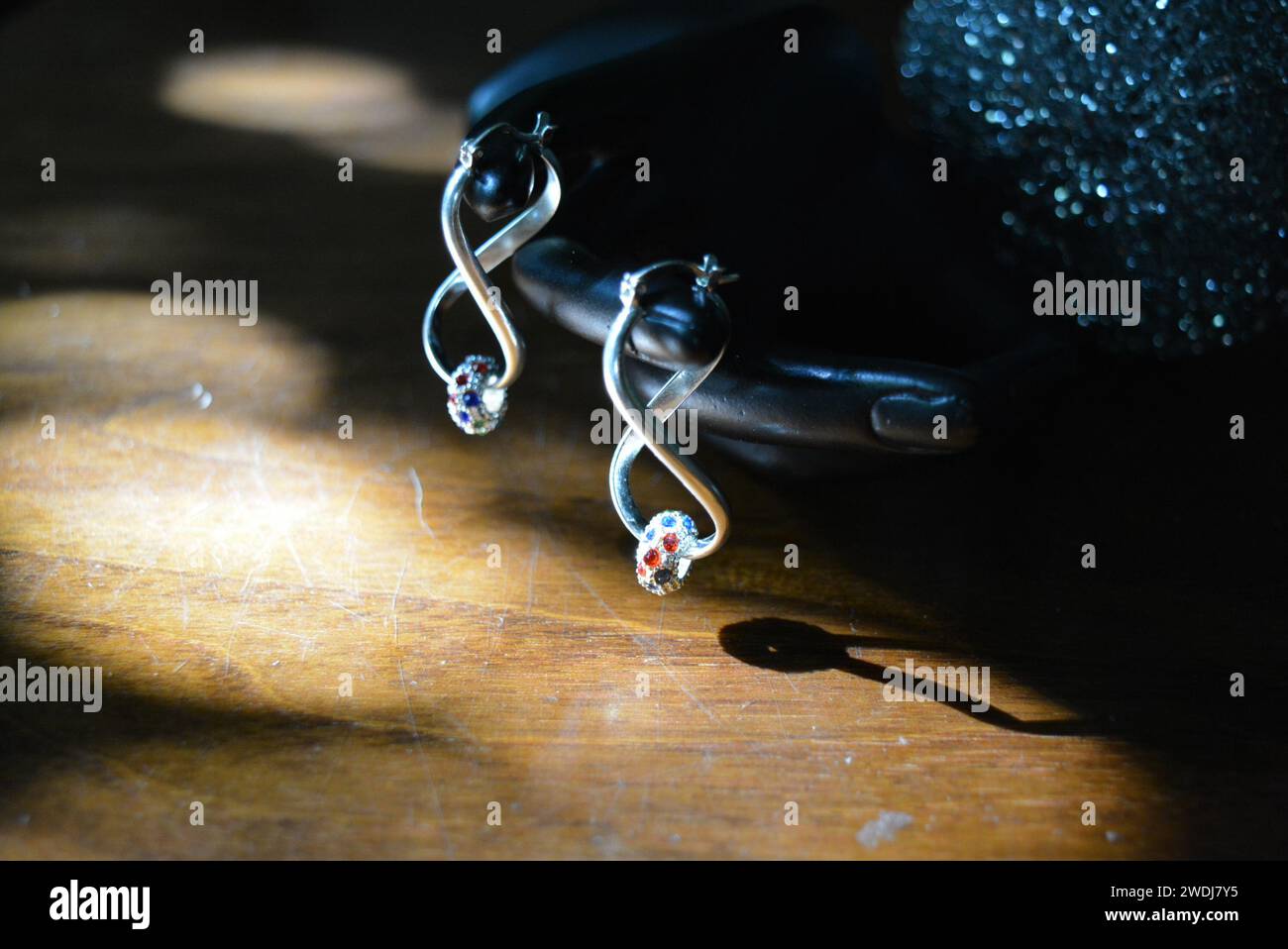 Statuette noire d'une main féminine mate avec boucles d'oreilles en argent avec de belles pierres et un pendentif. Banque D'Images