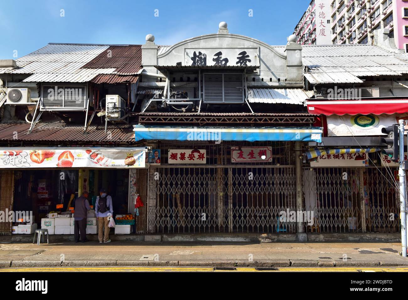 Marché aux fruits Yau Ma Tei, depuis 1913. Kowloon, Hong Kong. Anciens panneaux de magasins peints sur la façade des magasins à plusieurs étages, des quartiers d'habitation et des rangements à l'étage. Banque D'Images