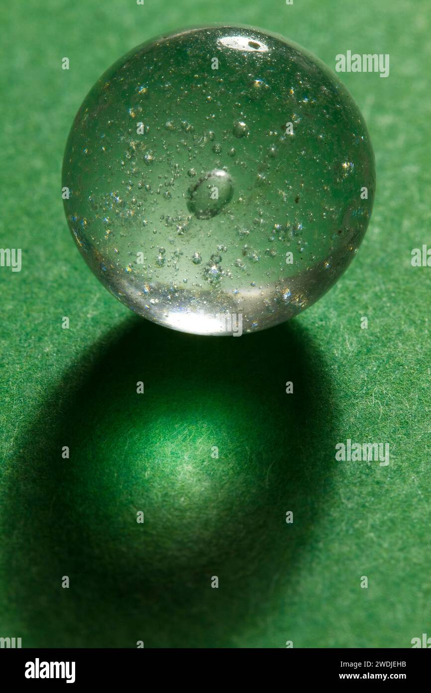 Un marbre de verre clair avec des bulles sur un fond vert. Banque D'Images