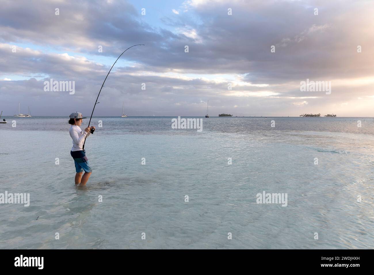 Touriste enfant en vacances, pêchant dans une eau peu profonde dans un lagon isolé d'une île tropicale de l'archipel de San Blas au coucher du soleil, Panama Banque D'Images