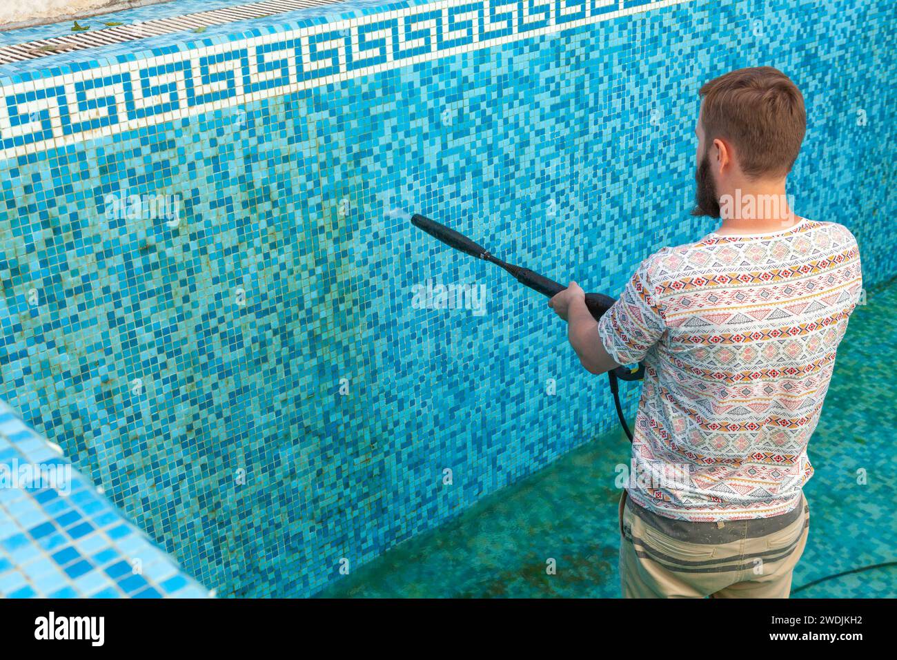 Service et entretien de la piscine. Piscine sale, nettoyage du sol de la piscine avec une machine à jet d'eau à haute pression. Banque D'Images