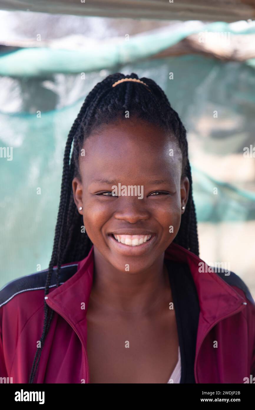 village souriant travailleur social africain jeune femme avec des tresses debout dans la cour Banque D'Images