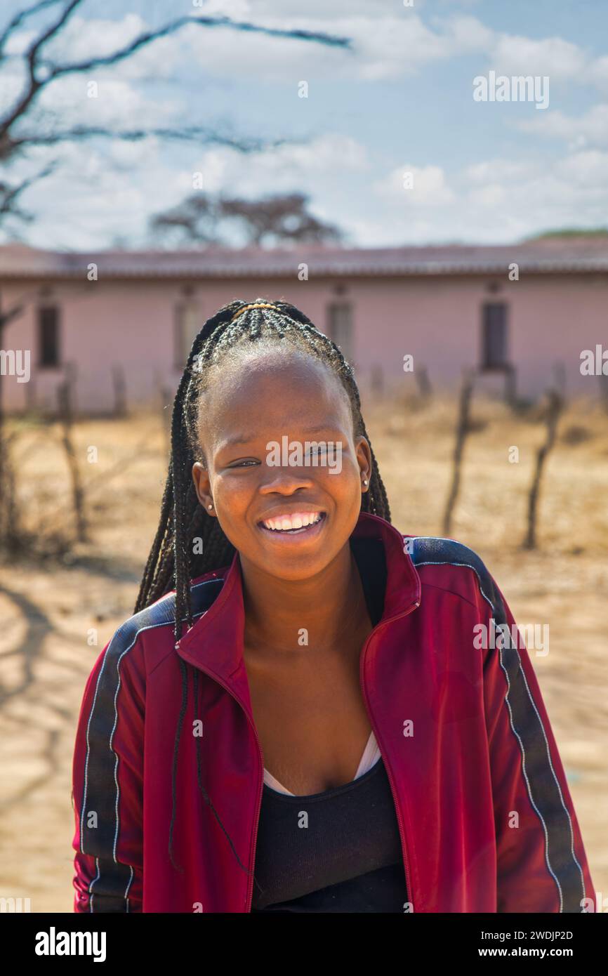 village souriant travailleur social africain jeune femme avec une tresse debout dans la cour Banque D'Images