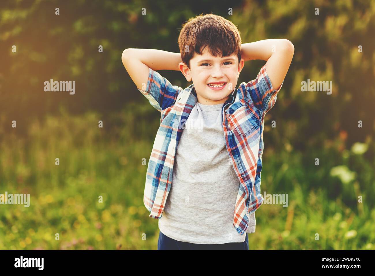 Joyeux garçon de 6 ans s'amusant à l'extérieur portant une chemise à carreaux bleue Banque D'Images