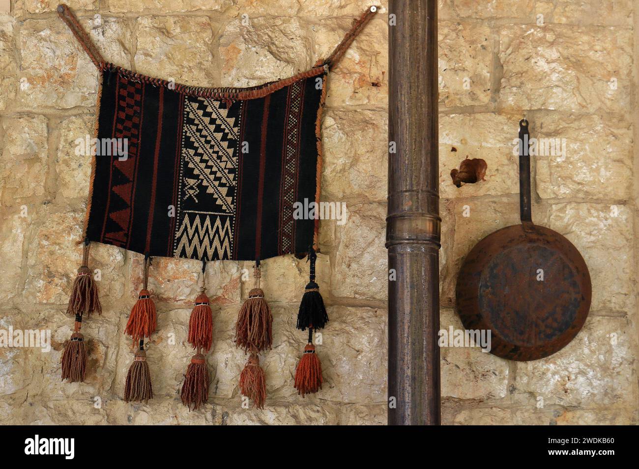 Tapis décoratif et poêle sur un mur intérieur en pierre, Banque D'Images