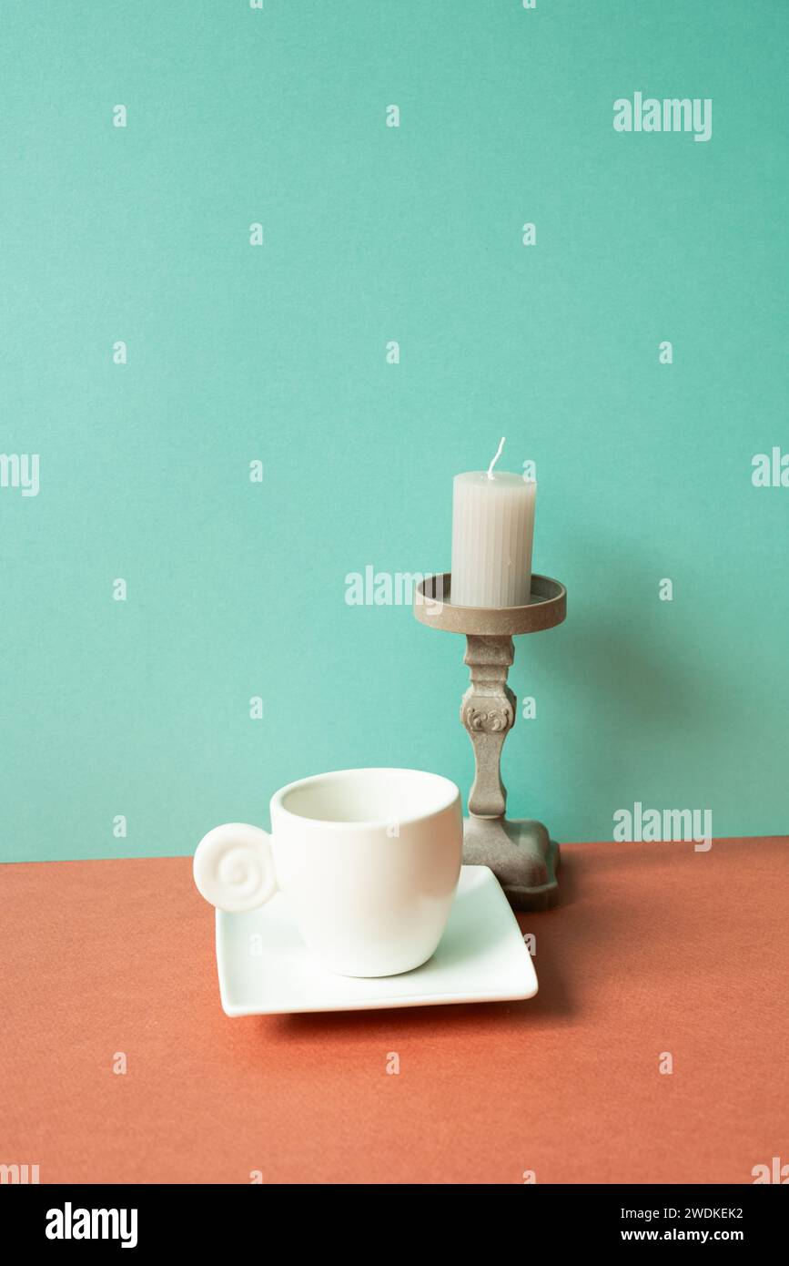 Tasse à café blanc avec bougie sur la table rouge. fond de mur vert menthe Banque D'Images