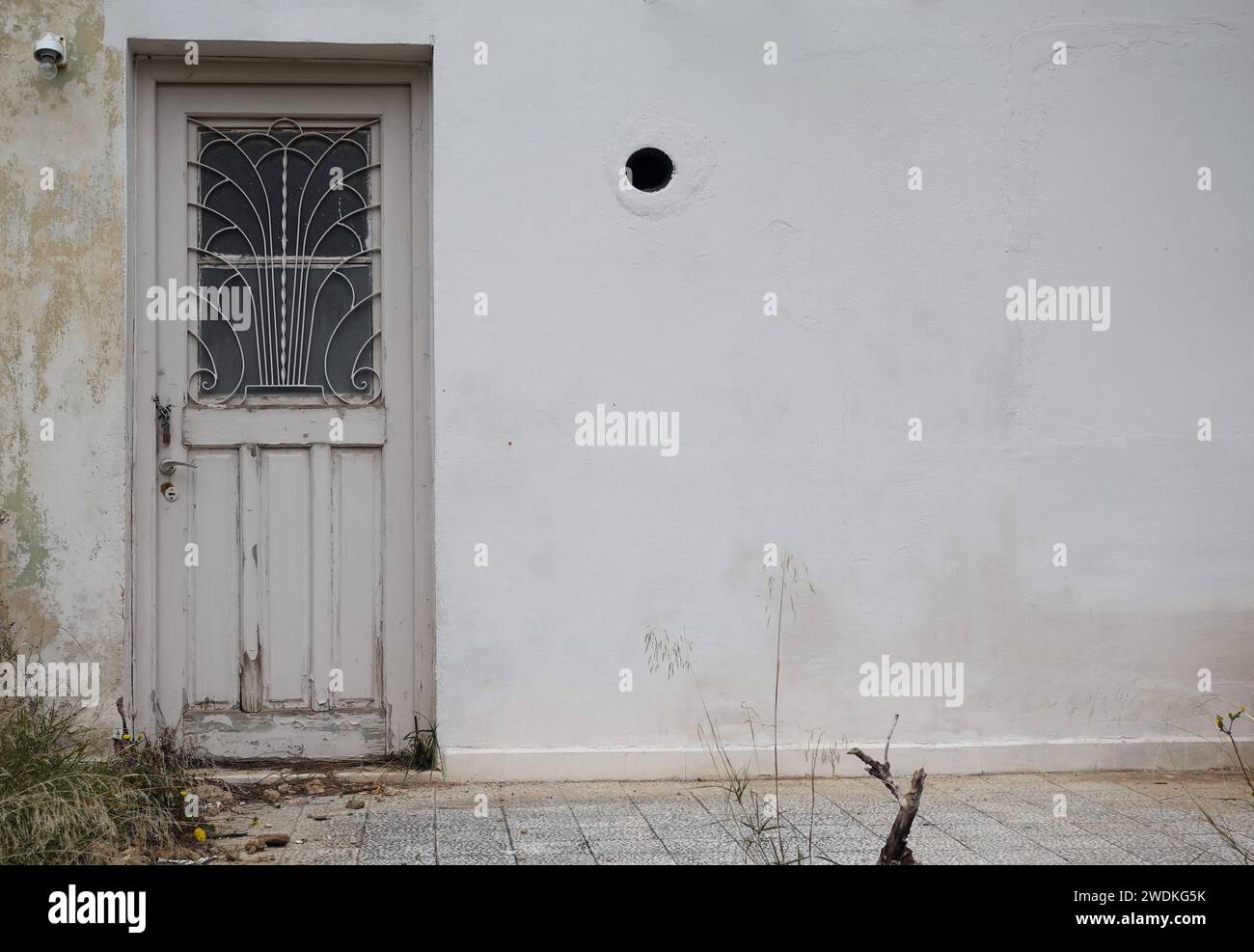 Vieille porte avec grille de grille en fer vintage design et mur texturé. Extérieur de la maison abandonnée. Banque D'Images