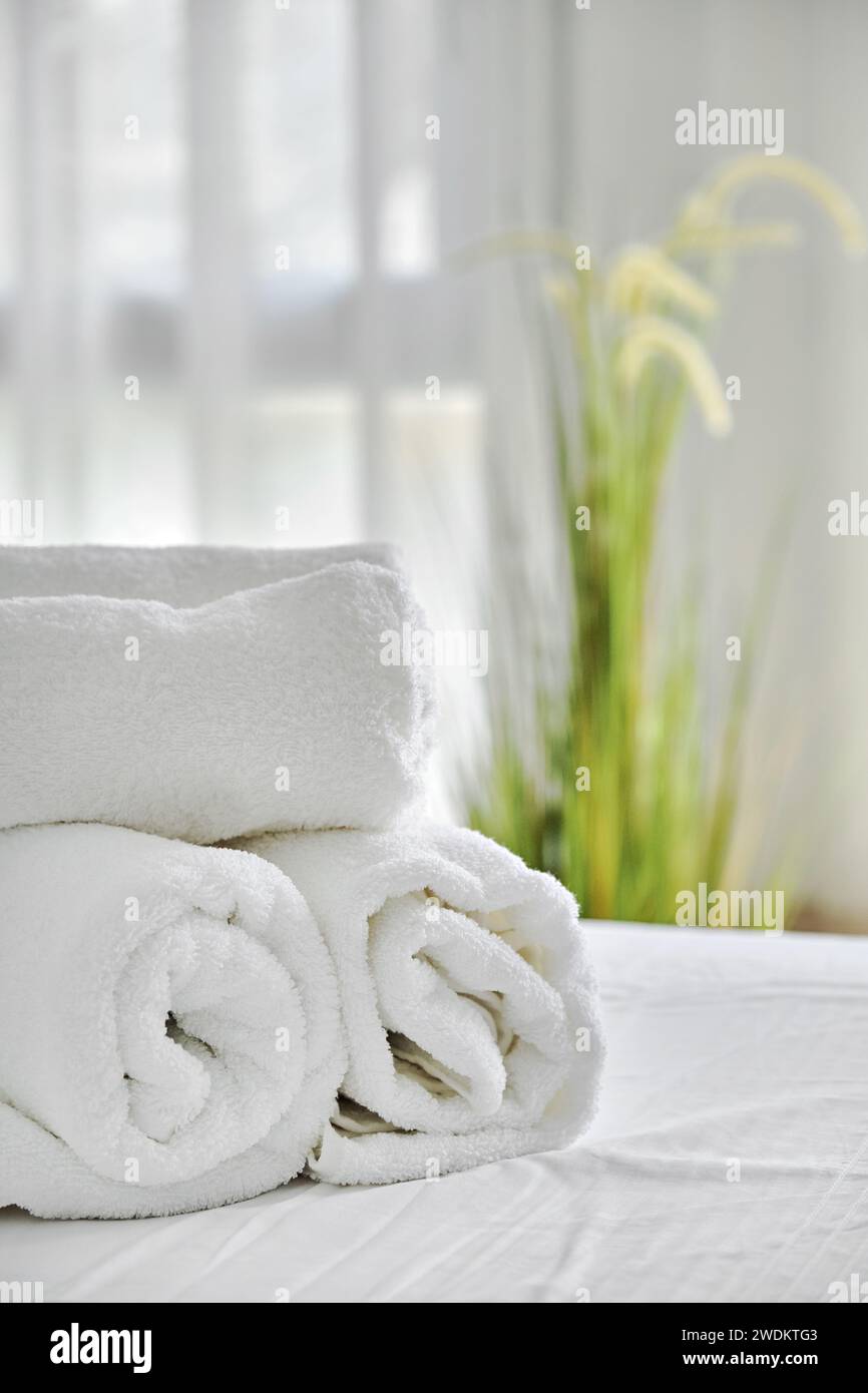 Trois serviettes blanches pliées sur le lit dans une chambre confortable, vue rapprochée. Hébergement, vacances et concept d'hygiène Banque D'Images
