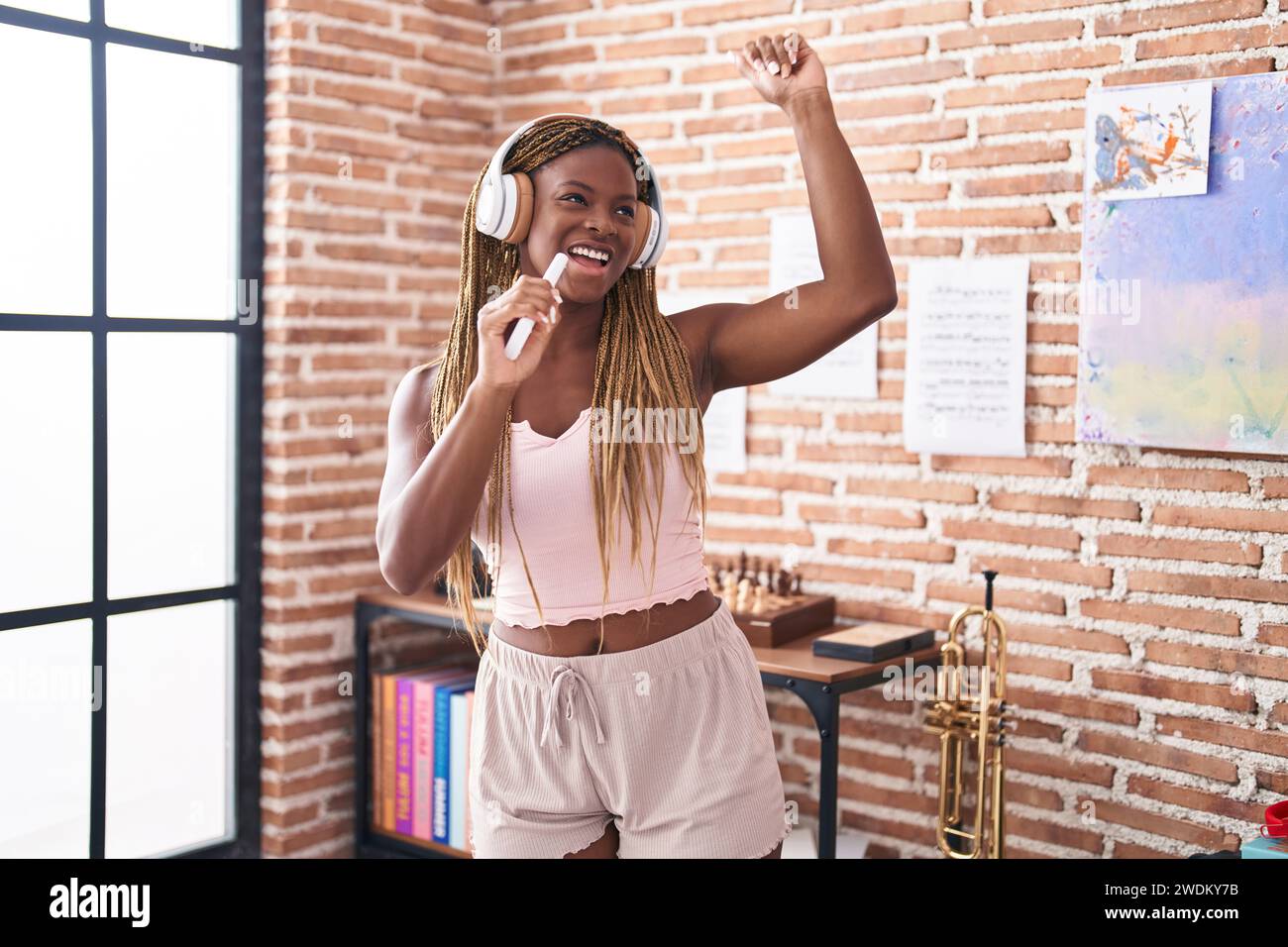 Femme afro-américaine écoutant de la musique chantant à la maison Banque D'Images