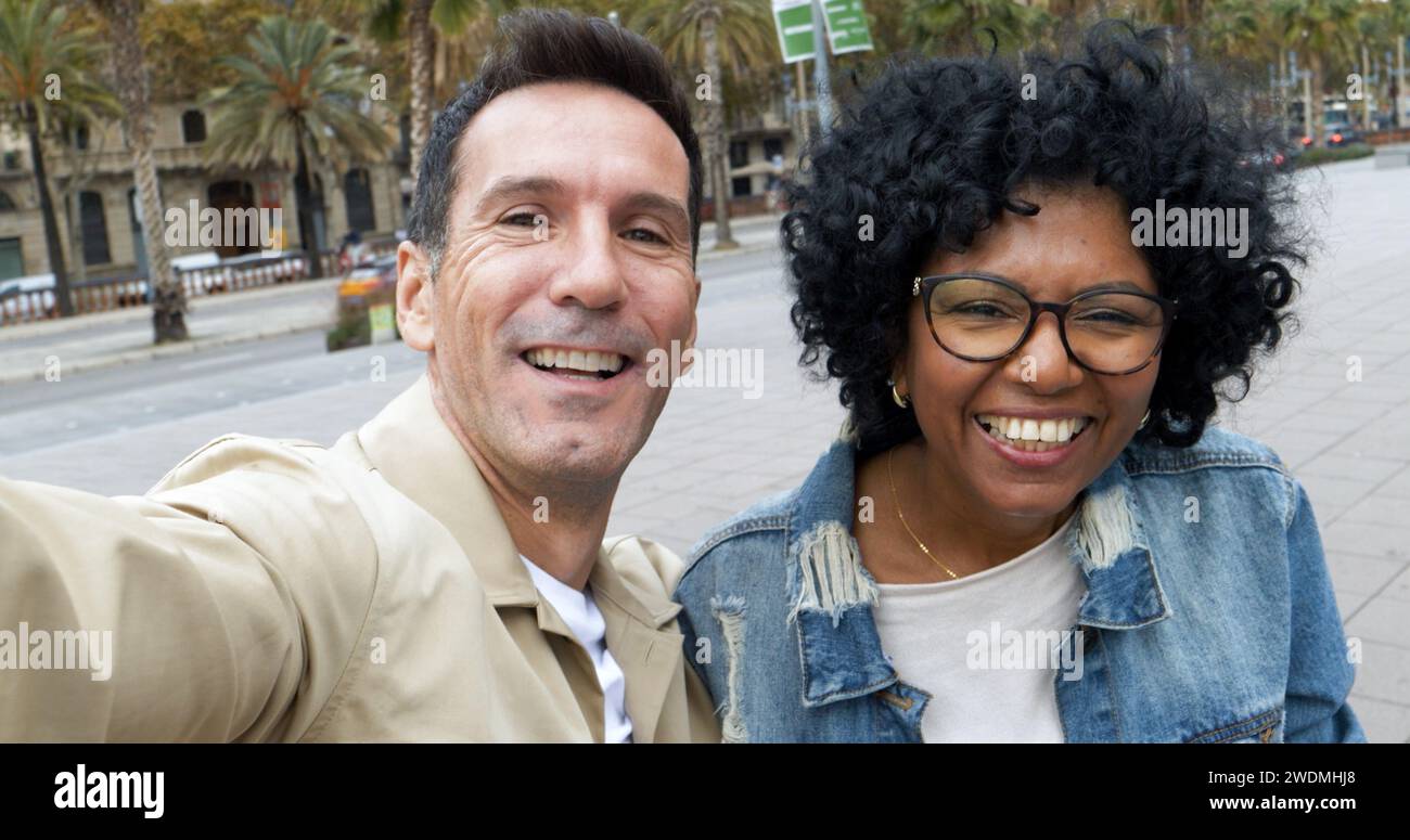 Perspective selfie d'un couple de touristes d'âge moyen diversifié prenant un selfie dans une ville. Couple hétérosexuel en vacances Banque D'Images