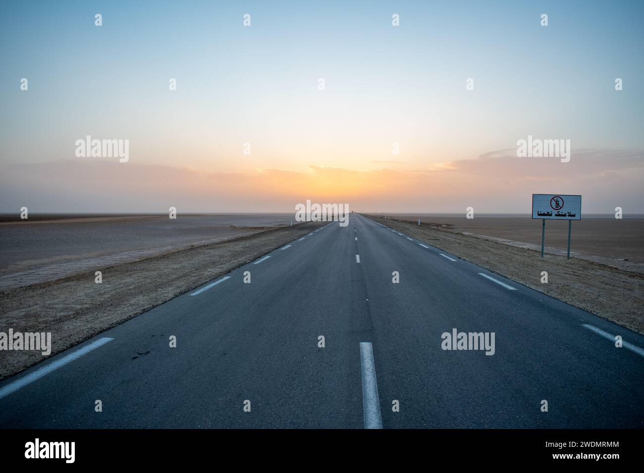 Panneau routier pas de signal en langue arabe. Magnifique coucher de soleil coloré sur une route asphaltée sans fin. Banque D'Images