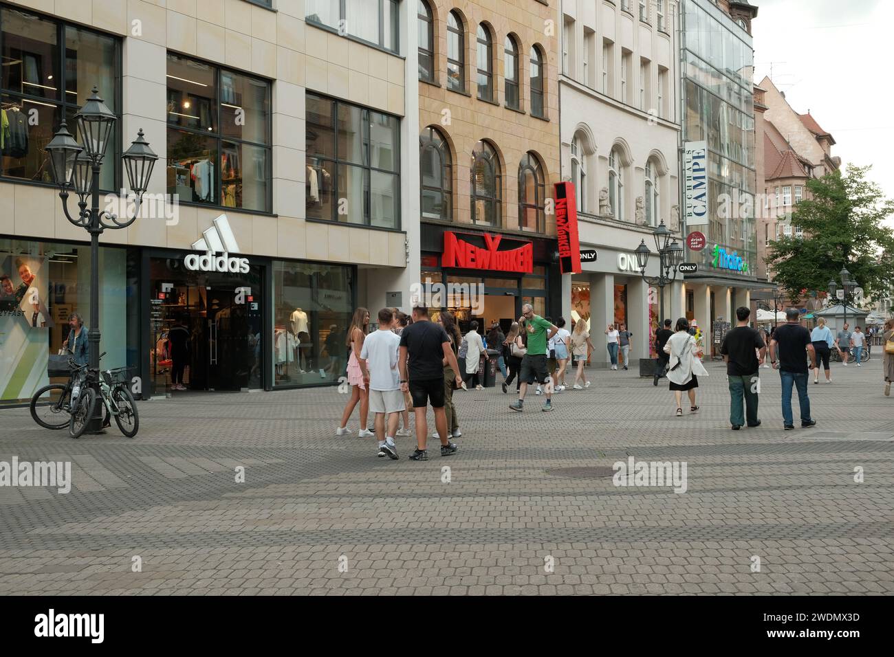 Plusieurs personnes se tiennent dehors sur Karolinenstraße avec divers grands magasins dans la ville allemande de Nuremberg. Banque D'Images