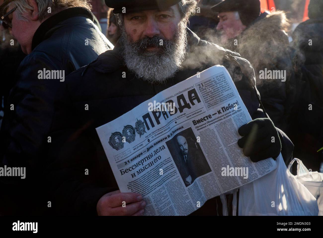 Moscou, Russie. 21 janvier 2024. Un partisan communiste russe porte un journal Pravda avec un portrait de Vladimir Lénine alors qu'ils marchent pour déposer des fleurs au mausolée du fondateur soviétique Vladimir Lénine pour marquer le 100e anniversaire de sa mort, sur la place Rouge, à Moscou, en Russie. Crédit : Nikolay Vinokurov/Alamy Live News Banque D'Images