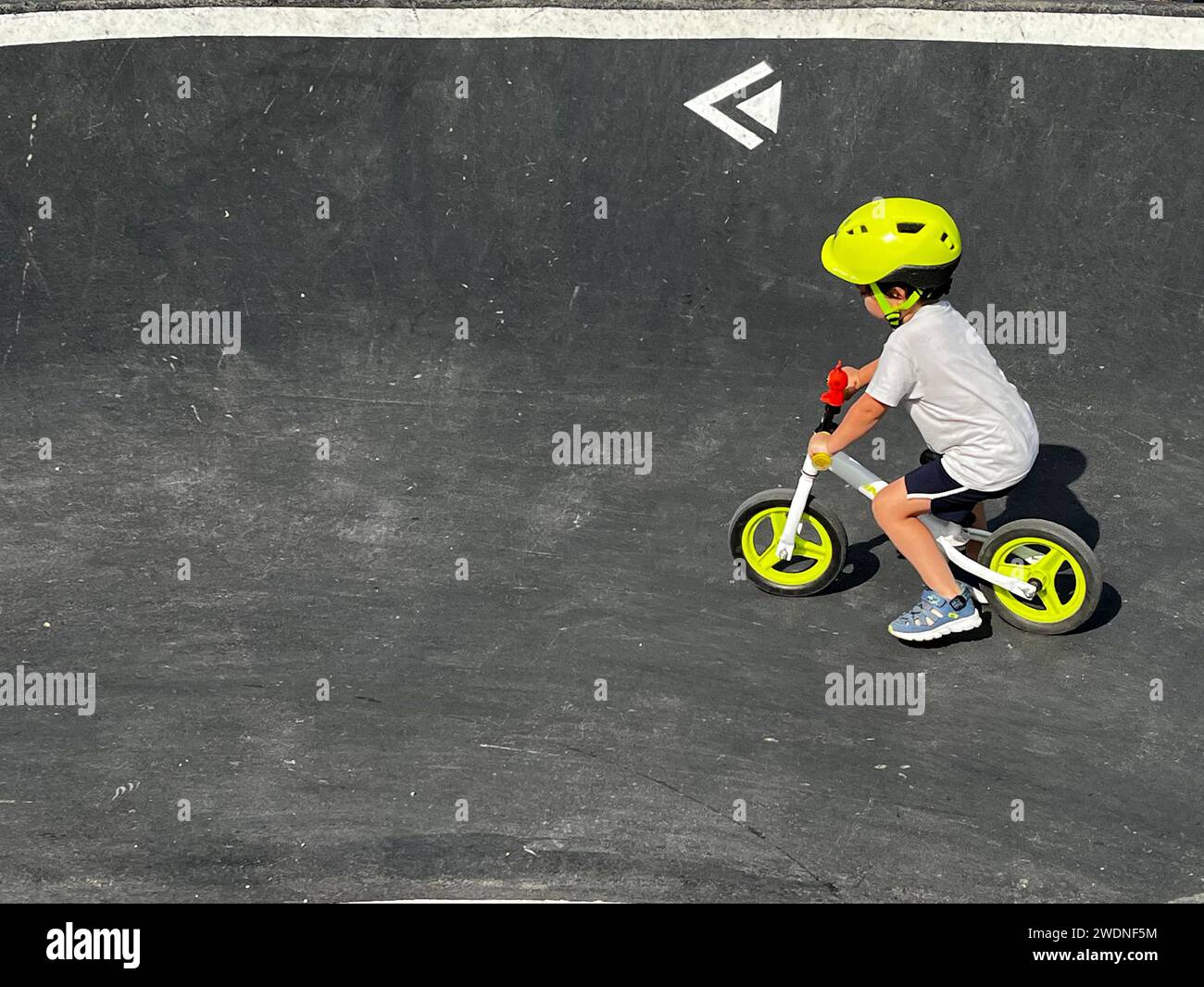 Vivifiant tour de pompe : enfant en casque sur un vélo blanc et vert fluorescent, la course à travers des virages passionnants Banque D'Images