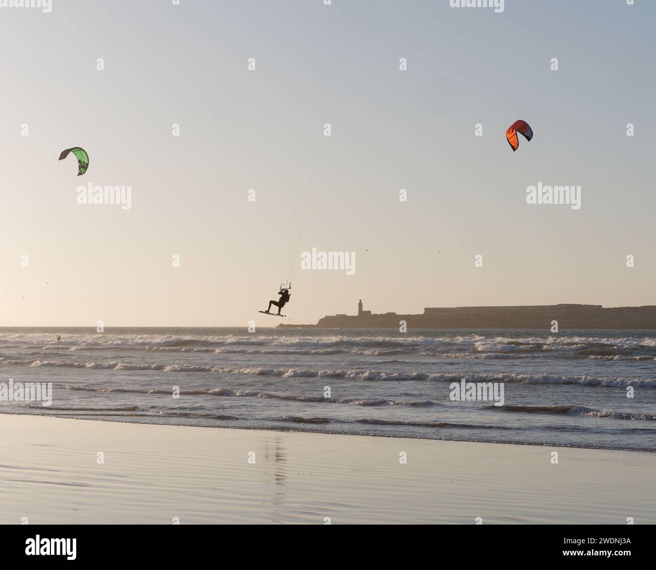 Kite surfeur dans les airs au coucher du soleil avec une île derrière à Essaouira, Maroc, 21 janvier 2024 Banque D'Images