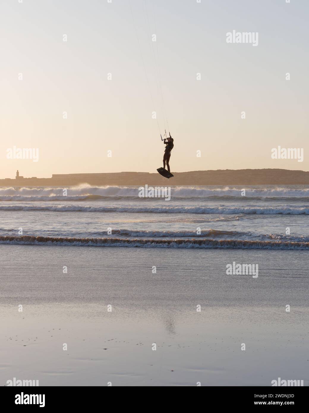 Kite surfeur dans les airs au coucher du soleil avec une île derrière à Essaouira, Maroc, 21 janvier 2024 Banque D'Images