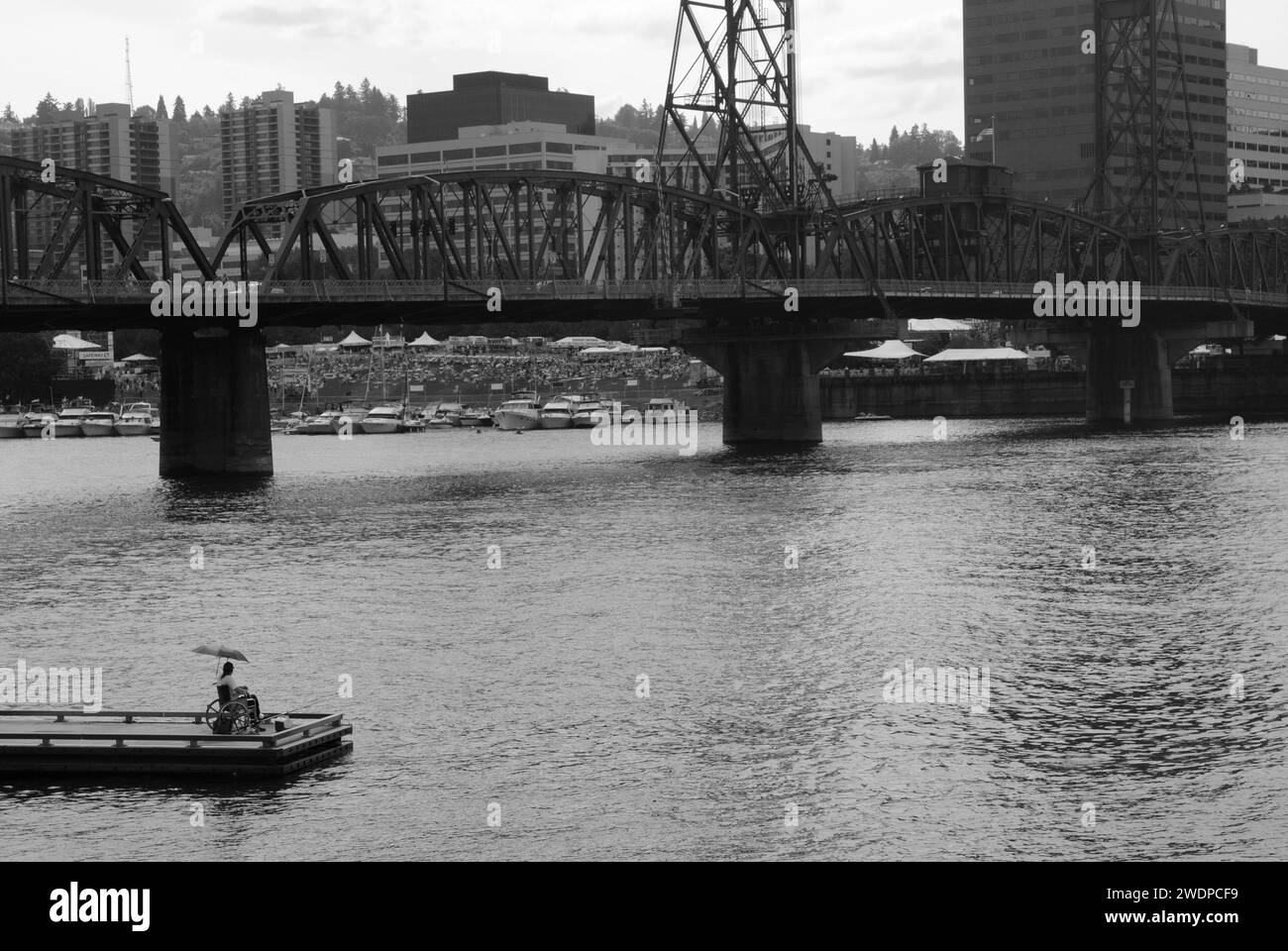 Un homme handicapé solitaire regarde de l'autre côté de la rivière Willamette à un concert dans le centre-ville de Portland, Oregon Banque D'Images