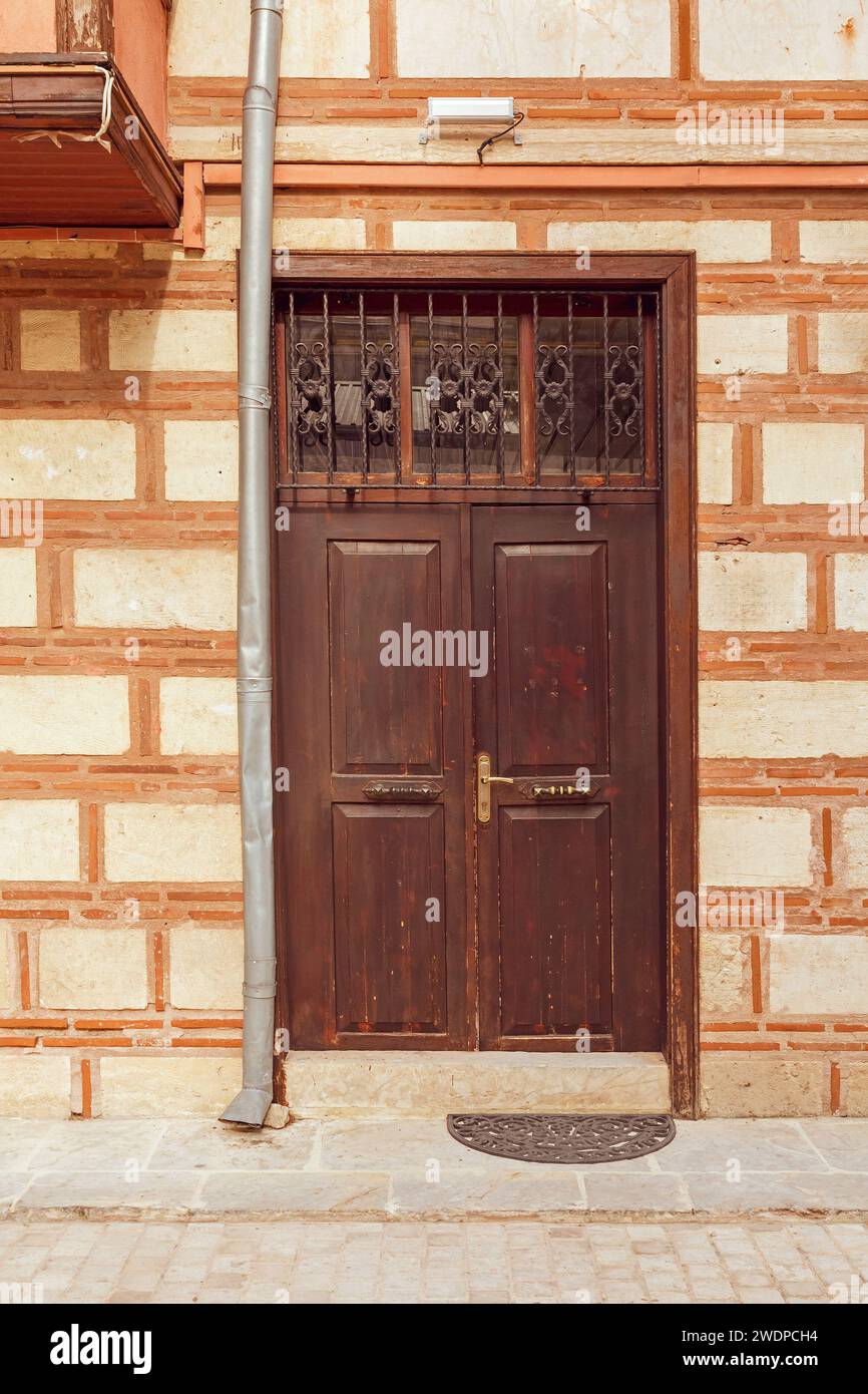 Vieille porte d'entrée en bois brun vintage fermée à l'extérieur avec façade en pierre Banque D'Images