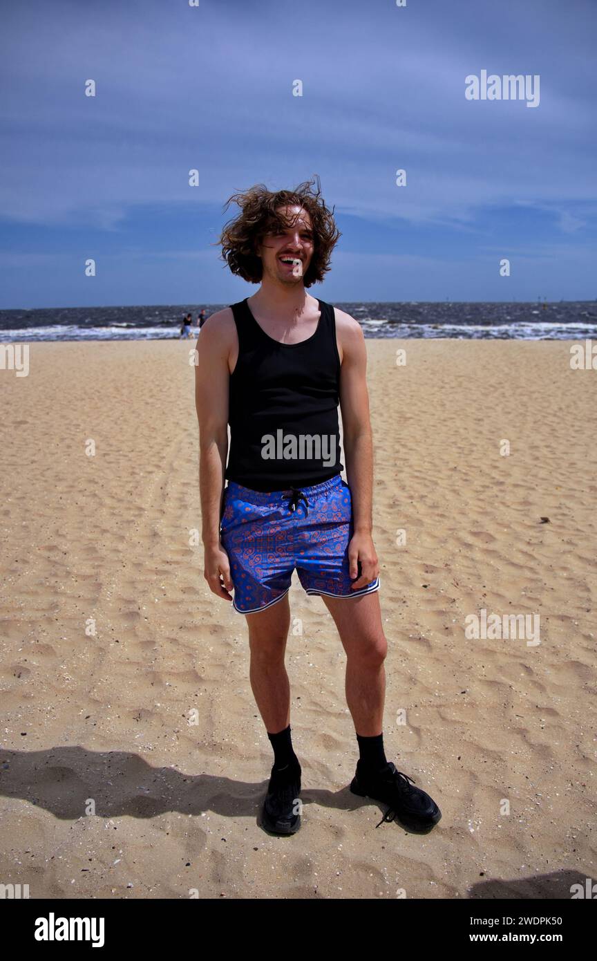 Jeune bel homme debout sur une plage de sable Banque D'Images
