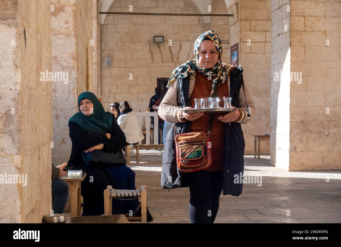 Femme Mardin servant du thé turc traditionnel, du chai turc sur un plateau dans un café à Mardin Medressi, en Turquie Banque D'Images